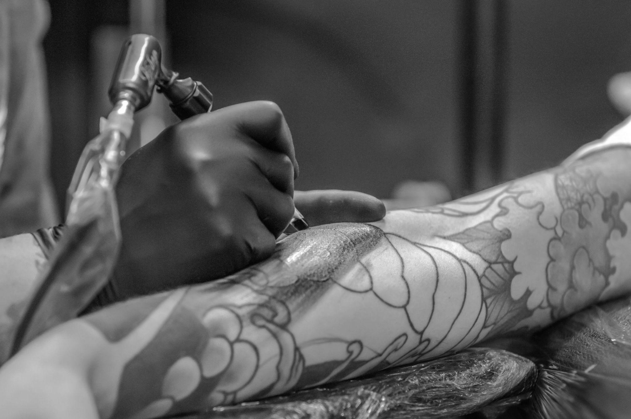 arm-tattoo-design-shop-1 artist applying a full sleeve tattoo