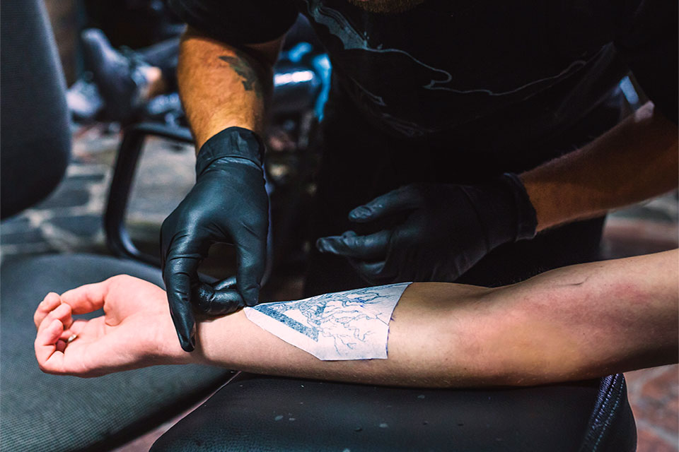 tattoo artist showing how to use tattoo transfer paper