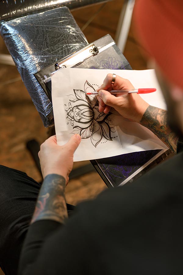established tattoo artist designing a lotus flower tattoo