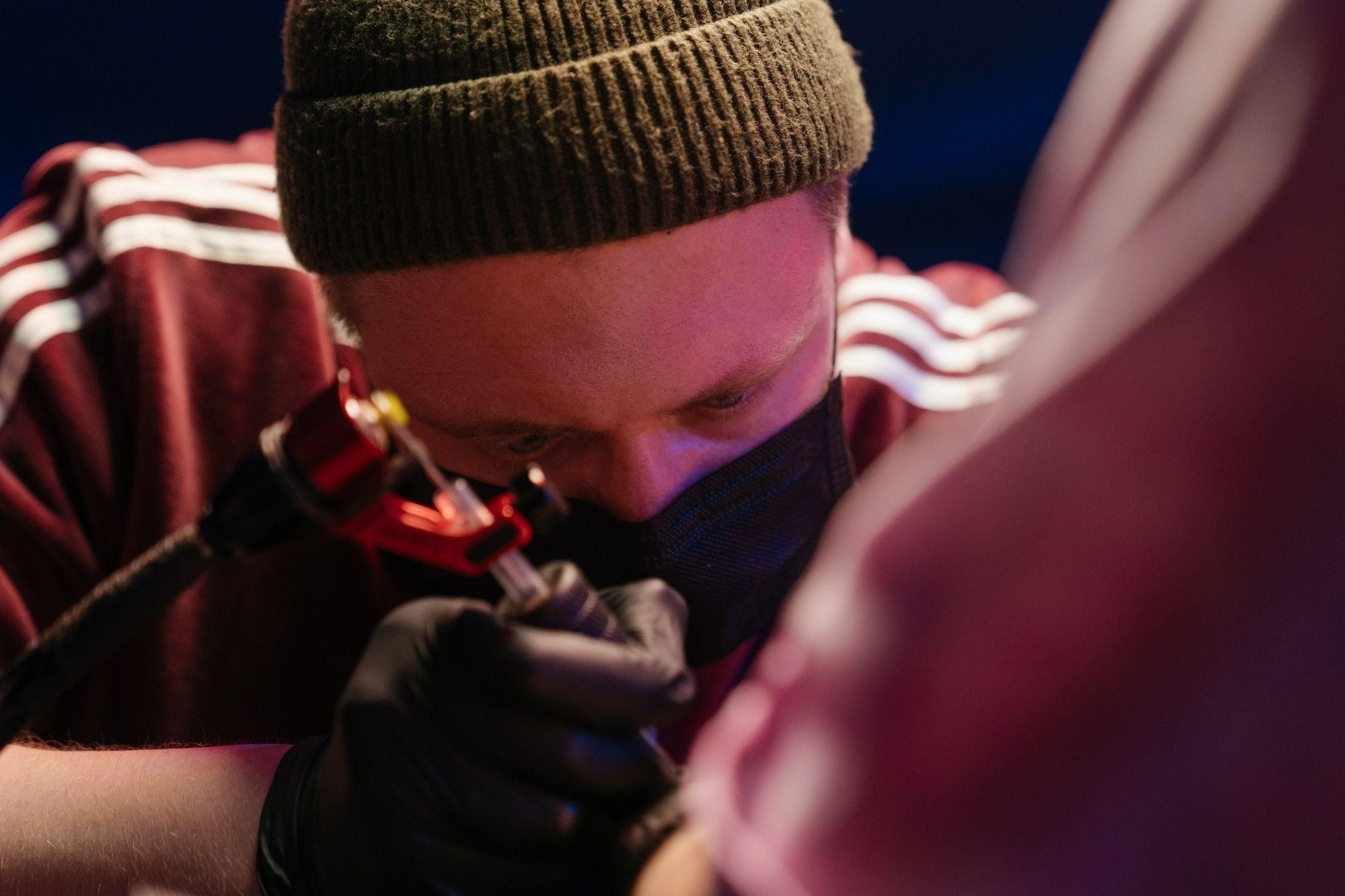 tattoo-artist-arm-tattoo tattoo artist applying a hand tattoo