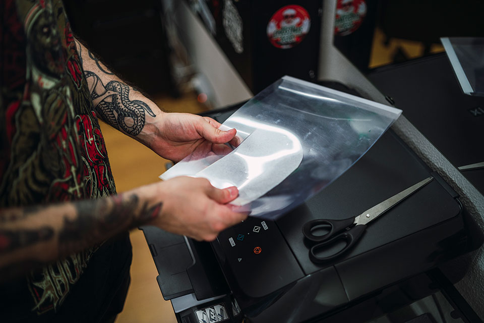 tattoo artist using tattoo stencil transfer paper in a tattoo shop