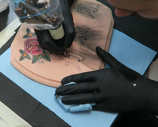 artist using tattoo ink and different needles on fake skin